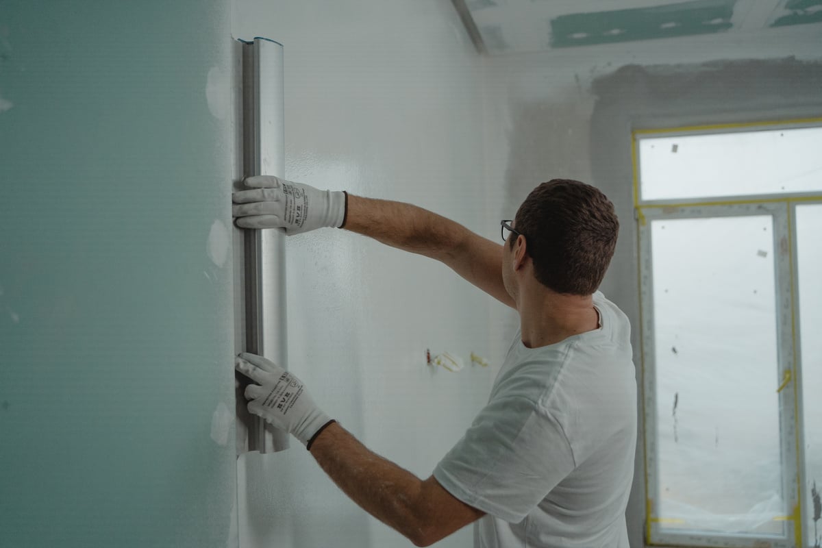 A Man in White Shirt Painting a House